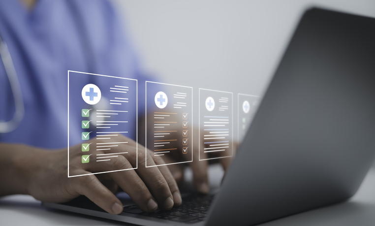 A person in a medical uniform with a stethoscope around their neck is typing on a laptop, with holographic medical checklists and checkmarks displayed above the keyboard.